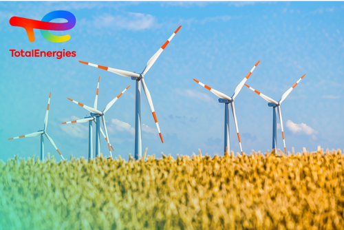 Wind turbines in a wheat field under a blue sky, with the colorful TotalEnergies logo in the top left corner.